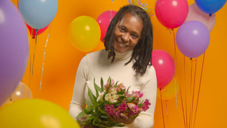 Studioporträt-Einer-Frau-Mit-Geburtstagsstirnband,-Die-Einen-Blumenstrauß-Hält-Und-Mit-Luftballons-Feiert
